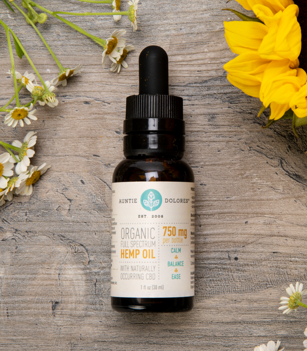 Image of Auntie Dolores 750 mg Organic Full Spectrum Hemp CBD Oil surrounded by flowers