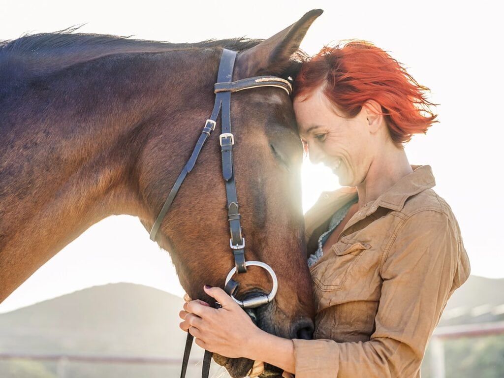 Profile photo of woman snuggling her horse who feels calmer after taking Treatibles hemp CBD oil for horses