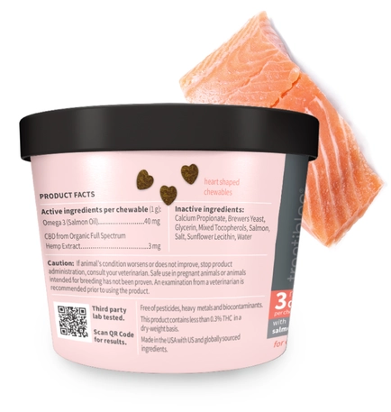 Image of the back of the pink canister of Treatibles Extra Strength CBD Soft Chewables for Dogs with a salmon filet behind it in the upper right corner